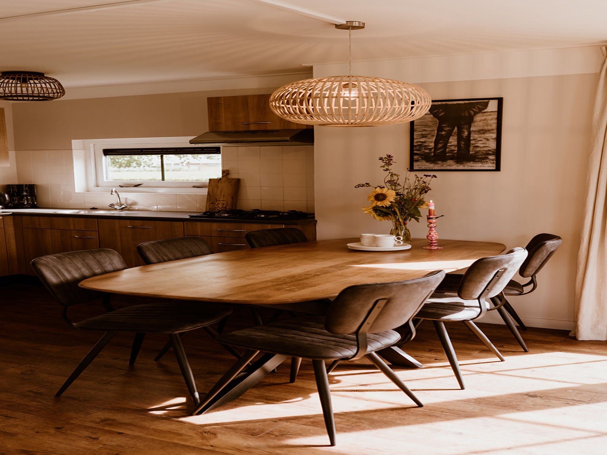 Een moderne keuken met een houten eettafel, stoelen en een hanglamp.
