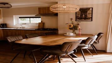 Een moderne keuken met een houten eettafel, stoelen en een hanglamp.