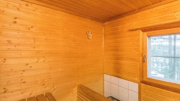 Puinen mökki sisältä, siellä on penkki, ikkuna ja laatoitettu seinä.