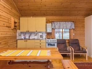 A compact kitchen with wooden cabinets, a stove, and a window with a curtain.
