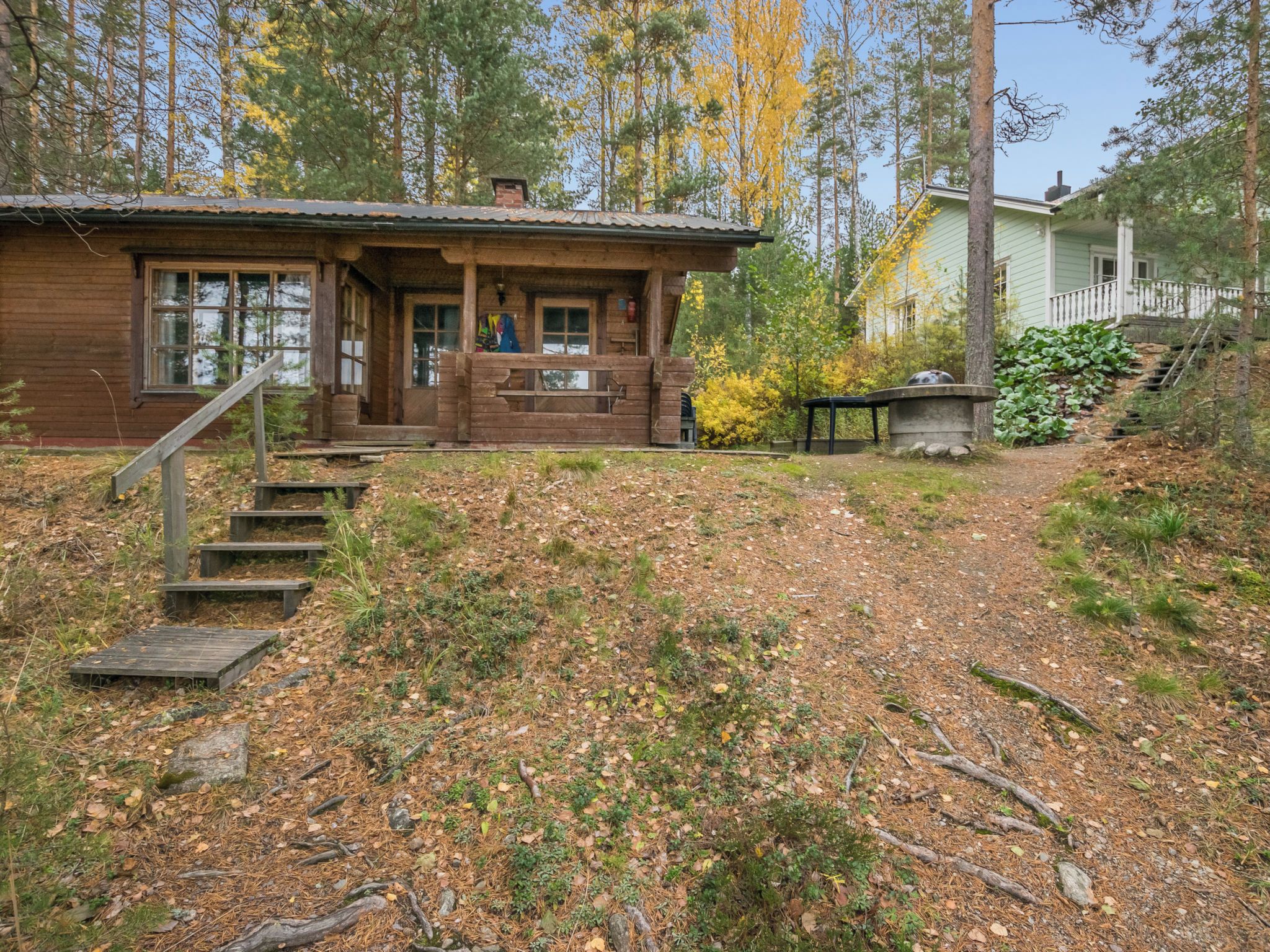 A cabin with a wooden exterior, a porch, and a staircase leading up to the entrance.