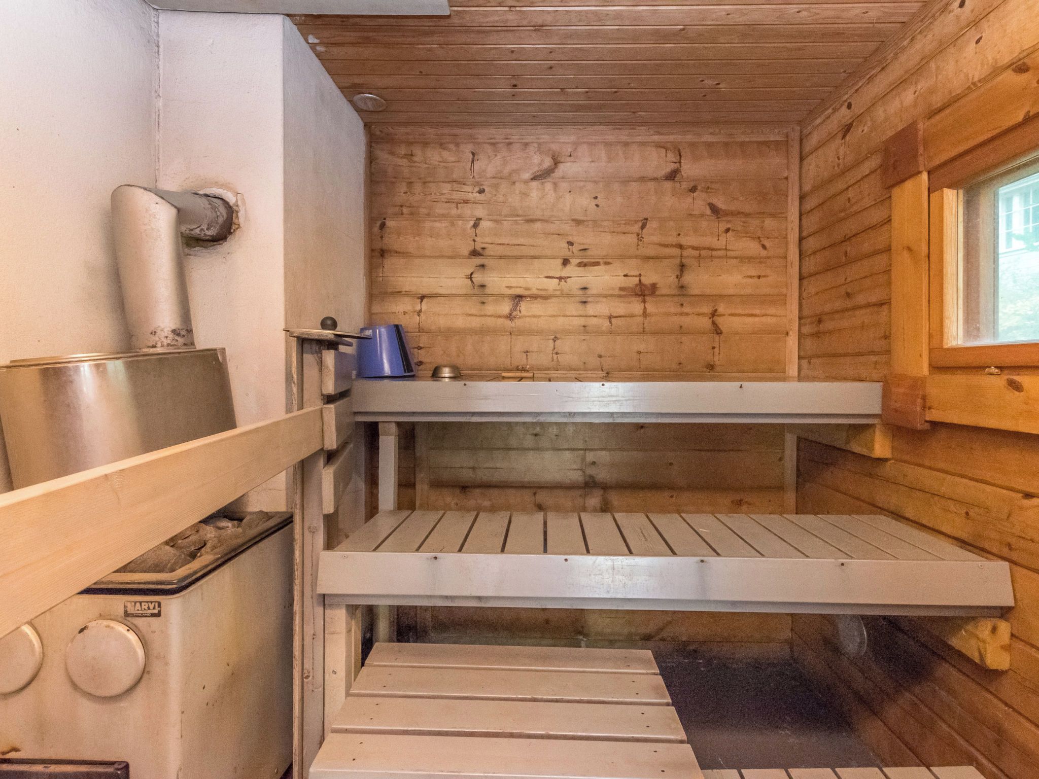 A sauna room with wooden walls, a bench, and a window.