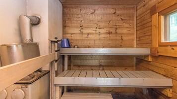 A sauna room with wooden walls, a bench, and a window.