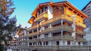 A multi-story hotel with wooden balconies and a ski slope in the background. - Les Cimes Blanches 102 A by Interhome (Nendaz)