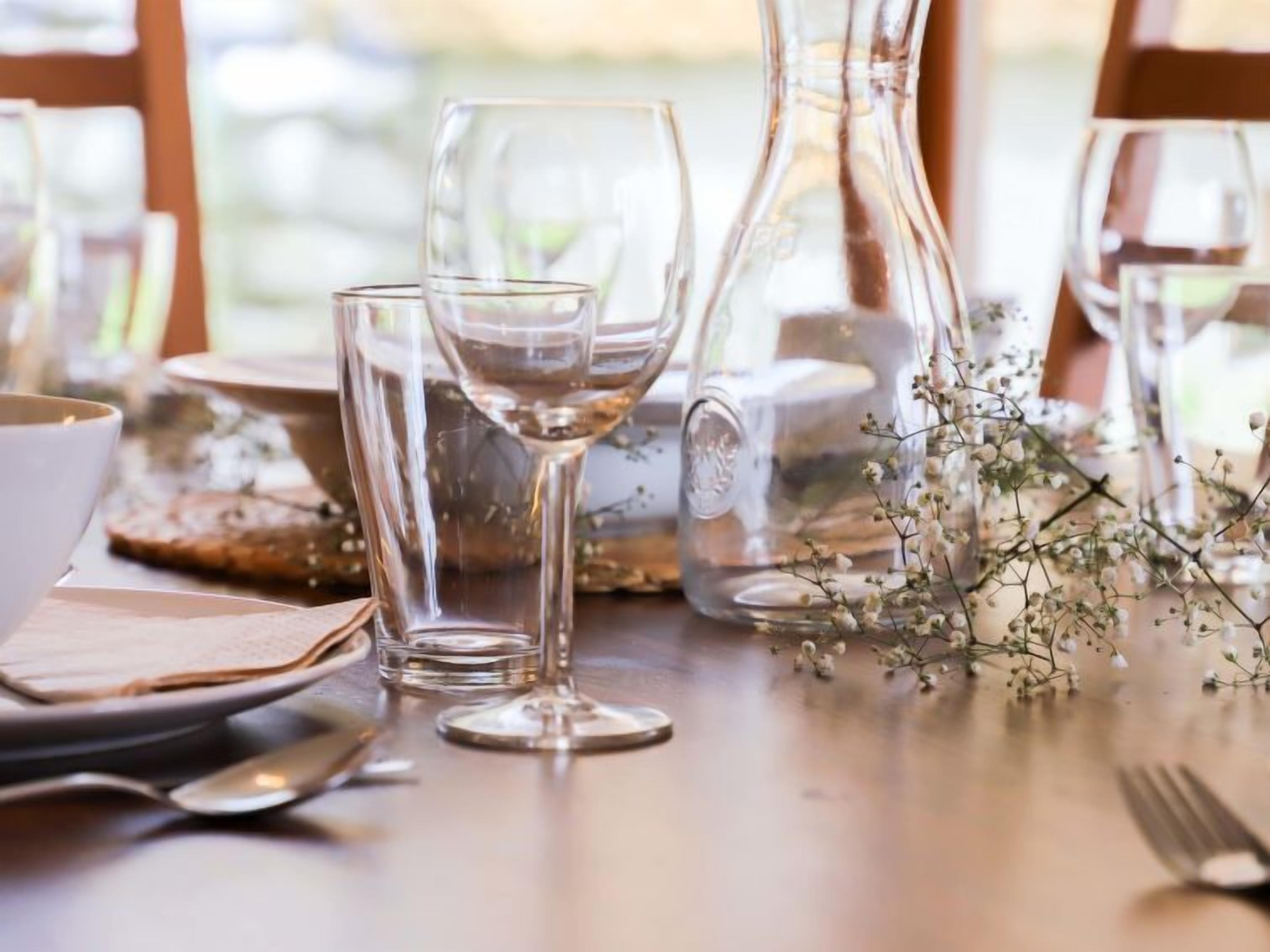 A table set with clear glassware, a pitcher, and a floral arrangement.