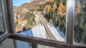 A view from a window of a mountainous landscape with a road, trees, and a building.