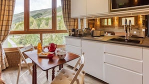A modern kitchen with a large window, white cabinetry, and a dining area with a table set for two.