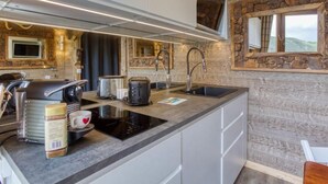 A modern kitchen with a stone accent wall, built-in appliances, and a large window.