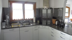 A kitchen with a sink, stove, and window with curtains. - Theresli by Interhome (Saas-Almagell)