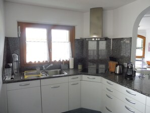 A kitchen with a sink, stove, and window with curtains.