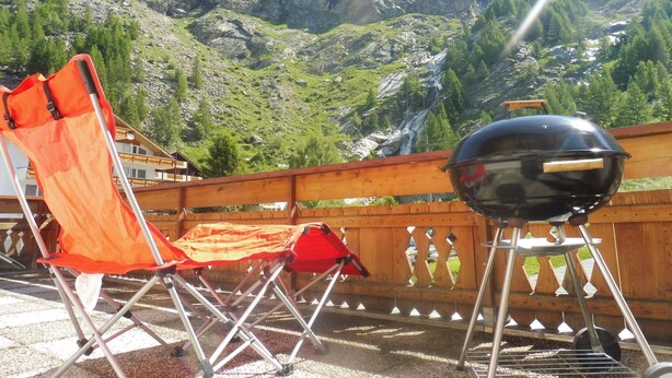 A balcony with a grill and a folding chair, overlooking a mountainous landscape. - Theresli by Interhome (Saas-Almagell)