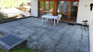 A balcony with a table and chairs, a wooden fence, and a view of a mountain. - Apartment Roger by Interhome (Zermatt)