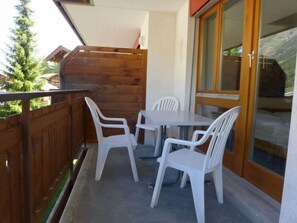 A balcony with a wooden fence, a table, and four white chairs.