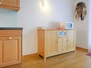 Cozinha com armários de madeira, micro-ondas e decoração geométrica no balcão.