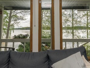 Una habitación con vistas a un lago y árboles a través de amplios ventanales.