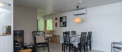 Un espace repas comprenant une table et des chaises, une cheminée et une vue sur l’extérieur.