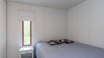 A bedroom with a single bed, a small bedside table, and a window with a white blind.