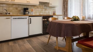 Una cucina moderna con mobili bianchi, una macchina da caffè e un'area pranzo con un tavolo apparecchiato per due.