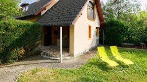 Ein Haus mit einem geneigten Dach, einer kleinen Veranda und einem Steinweg, der zum Eingang führt.