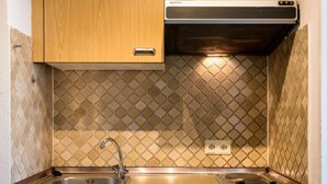 A compact kitchen with a stainless steel sink, a stove, and wooden cabinets. - Baumblick (B610) by Interhome (Lahnstein (Koblenz))