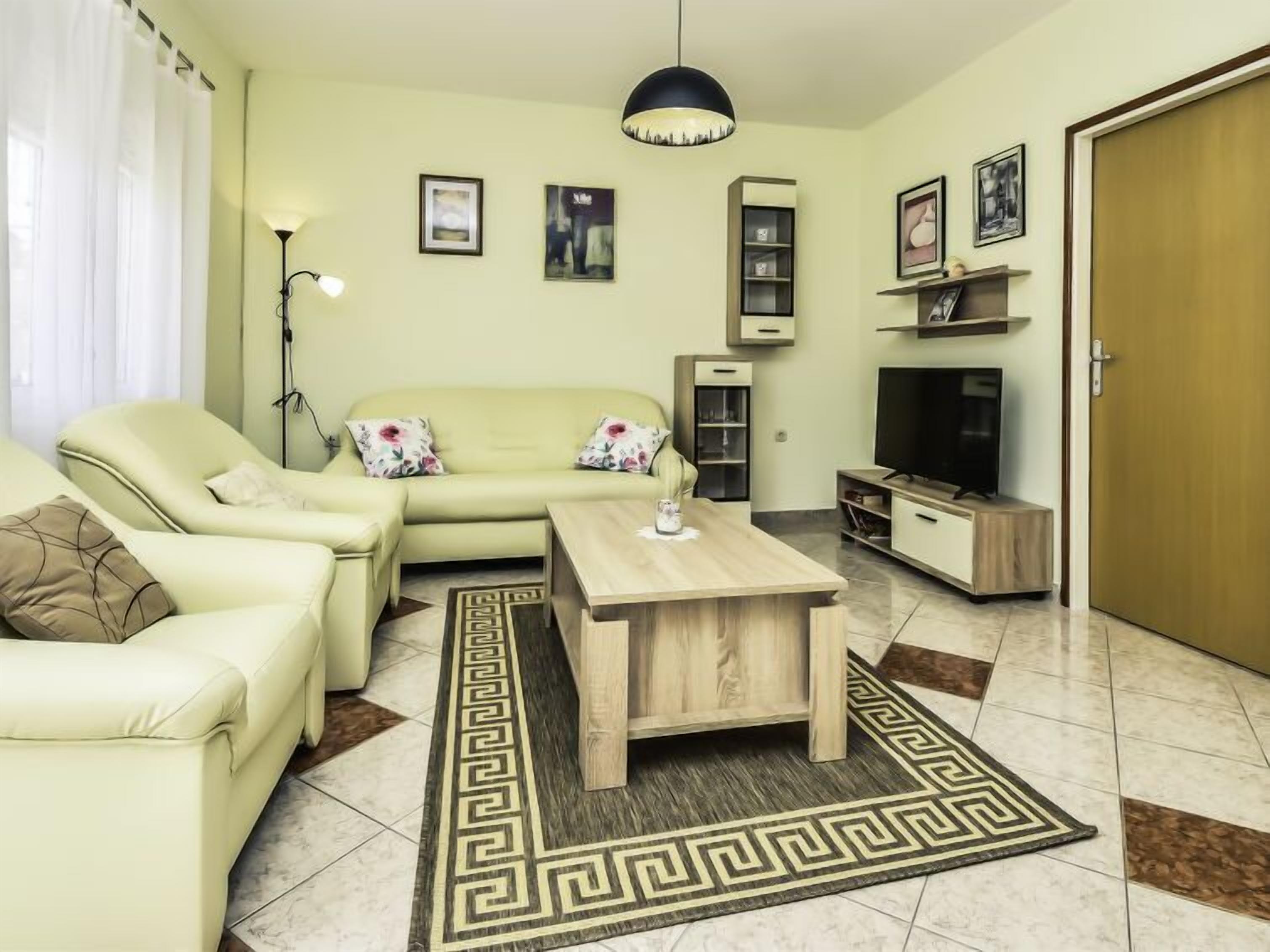 Una sala de estar con un sofá, una mesa de centro, un televisor y una estantería.