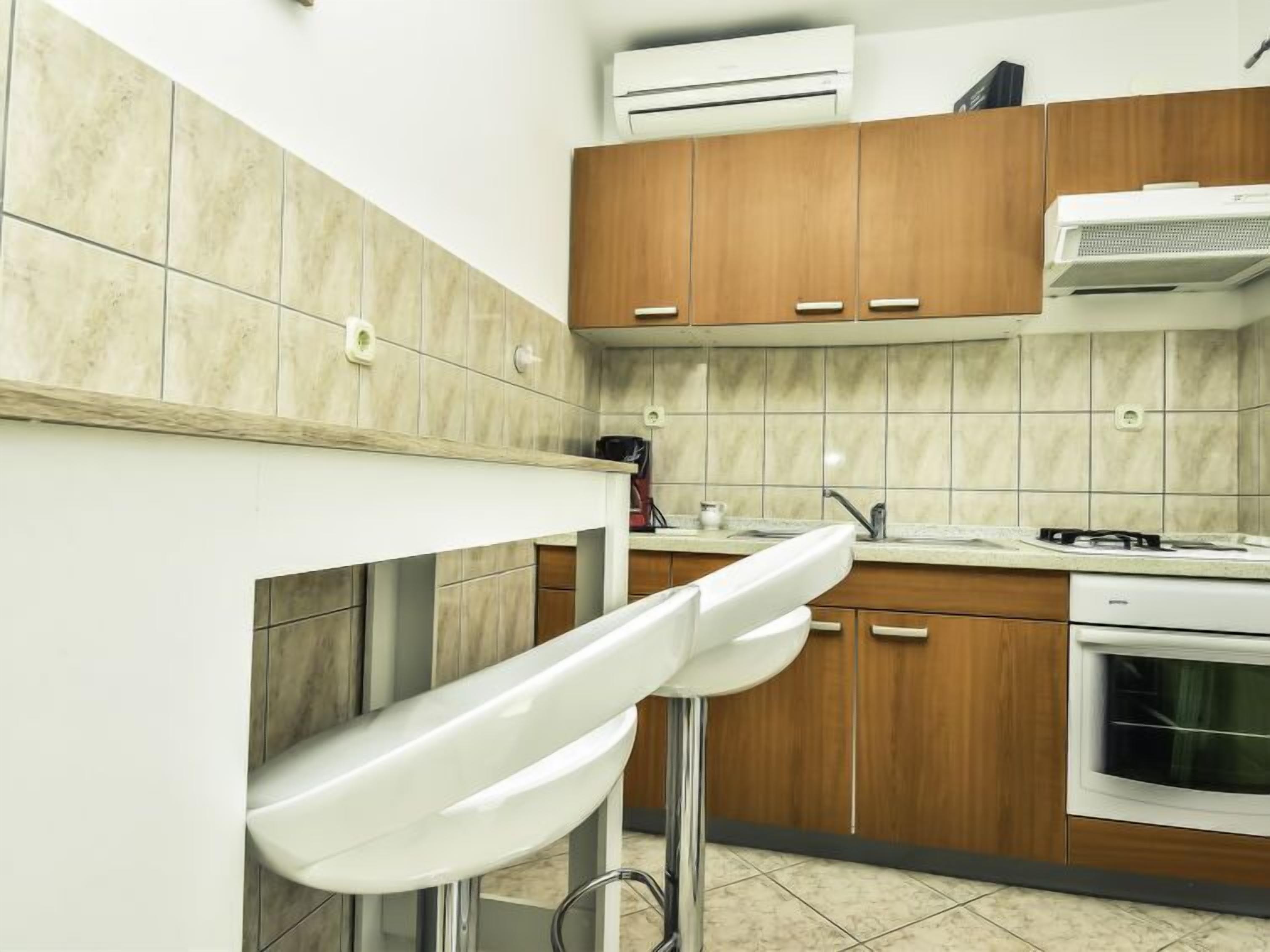 A modern kitchen with wooden cabinets, a white countertop, and a built-in oven.
