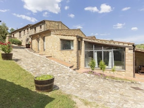 A stone building with a covered patio and a staircase leading to a second floor.