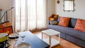 A living room with a sofa, a small table, and a dining table with plates and glasses. - Les Girolles B14 by Interhome (Villars)