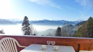 A white table with two cups and two wine glasses on a balcony overlooking a mountainous landscape. - Les Girolles B14 by Interhome (Villars)