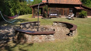 Uma cabana rústica com uma lareira de pedra, uma rede e um deck de madeira.
