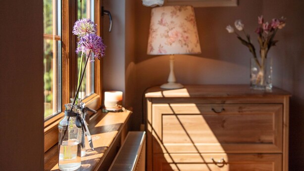 Um piano, uma lâmpada e um vaso com flores sobre uma mesa de madeira.