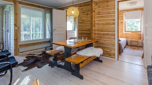 Un interior de madera con una mesa de comedor, bancos y una lámpara colgante.