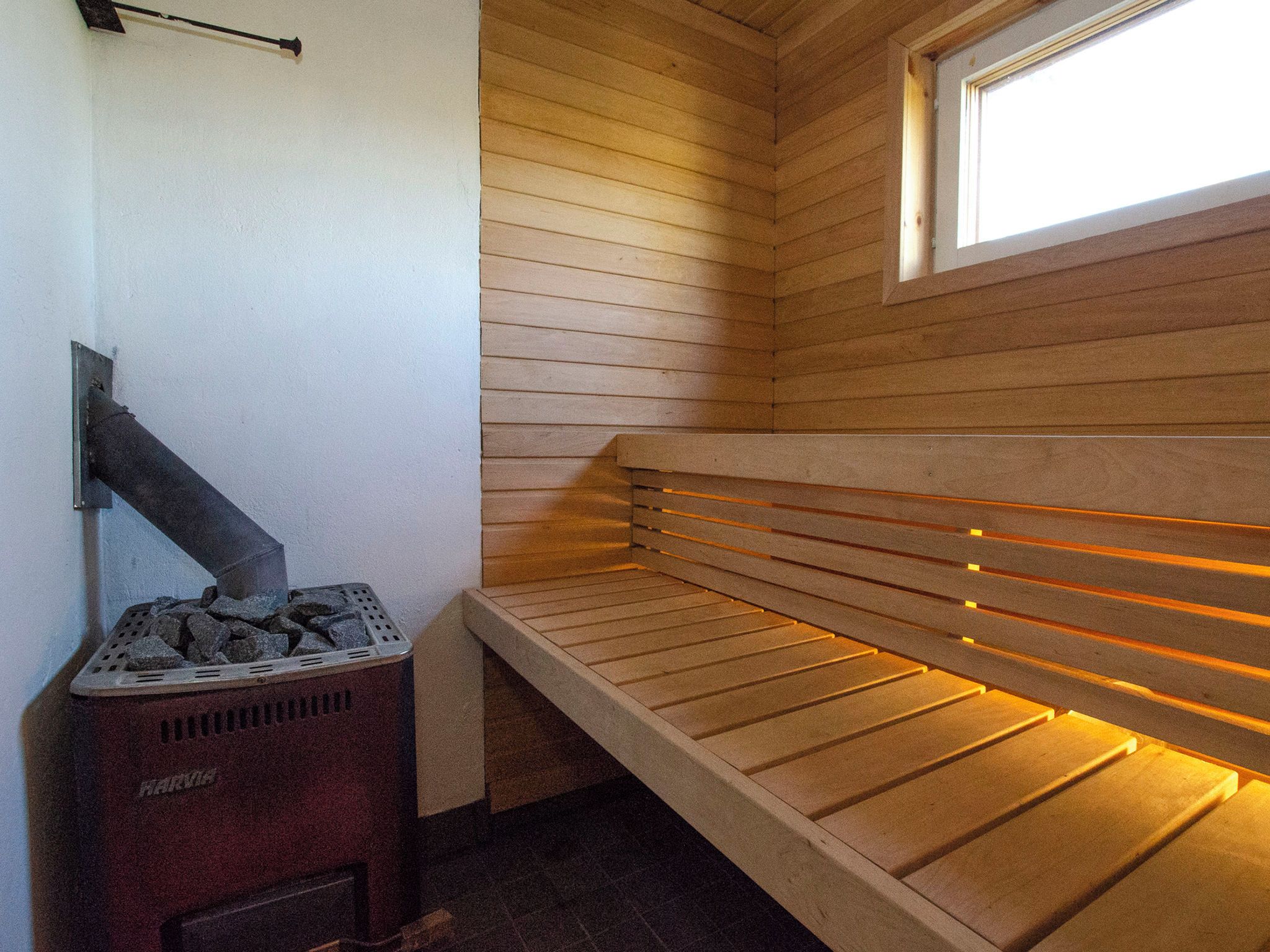 Un sauna équipé d’un banc, d’un radiateur fixé au mur et d’une fenêtre.