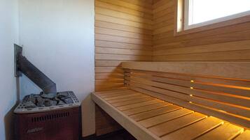 Un sauna équipé d’un banc, d’un radiateur fixé au mur et d’une fenêtre.