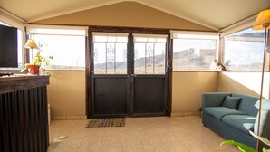 A room with a large sliding door, a sofa, a television, and a potted plant.