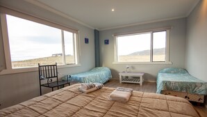 A bedroom with two beds, a chair, and a small table.