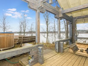 Une terrasse en bois avec un jacuzzi et des bancs, donnant sur un lac gelé.