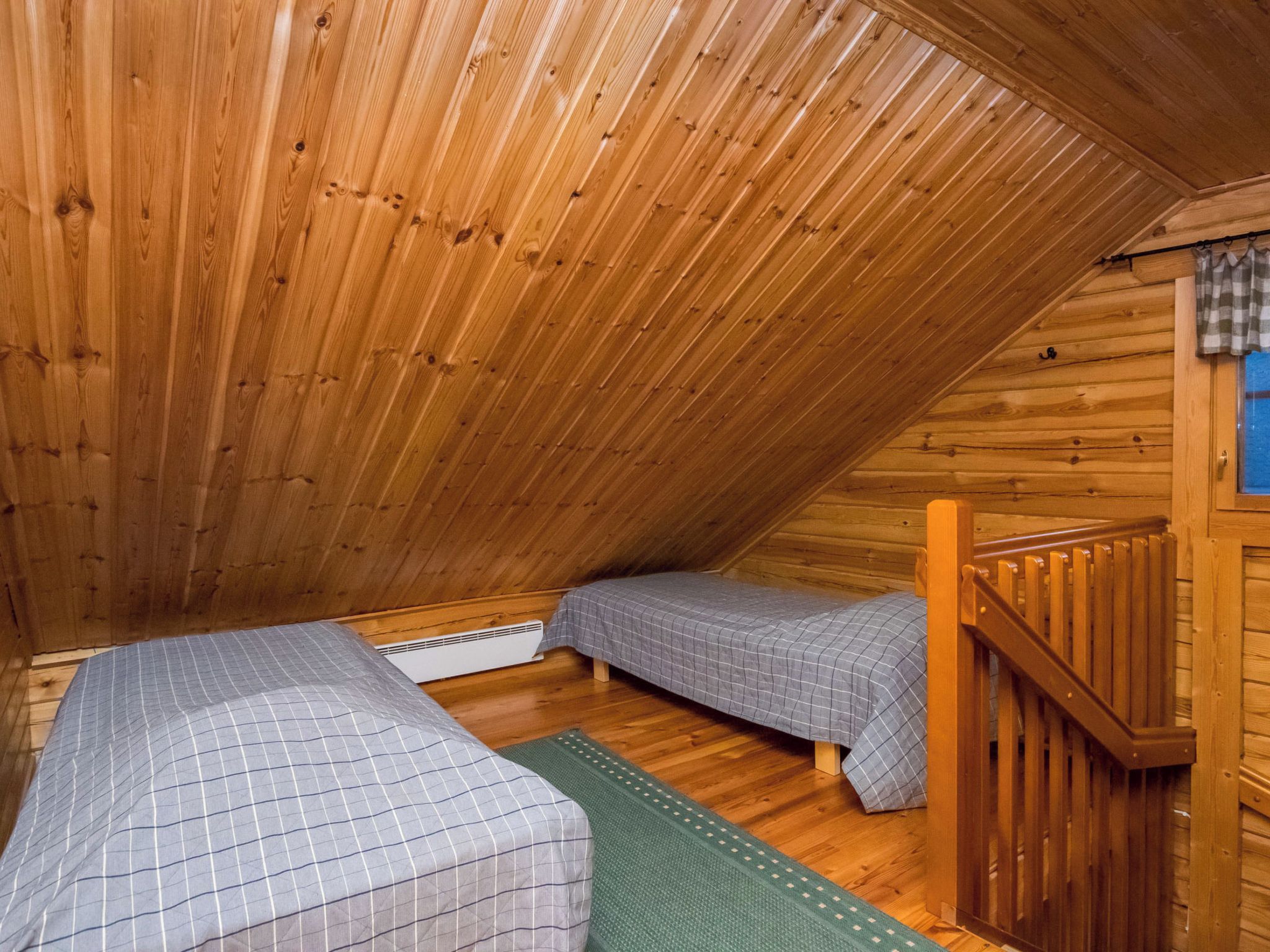 A small, cozy attic bedroom with wooden walls and sloped ceilings.