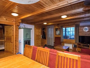 Un intérieur en bois avec une table à manger, un canapé rouge recouvert de tissu et un téléviseur.