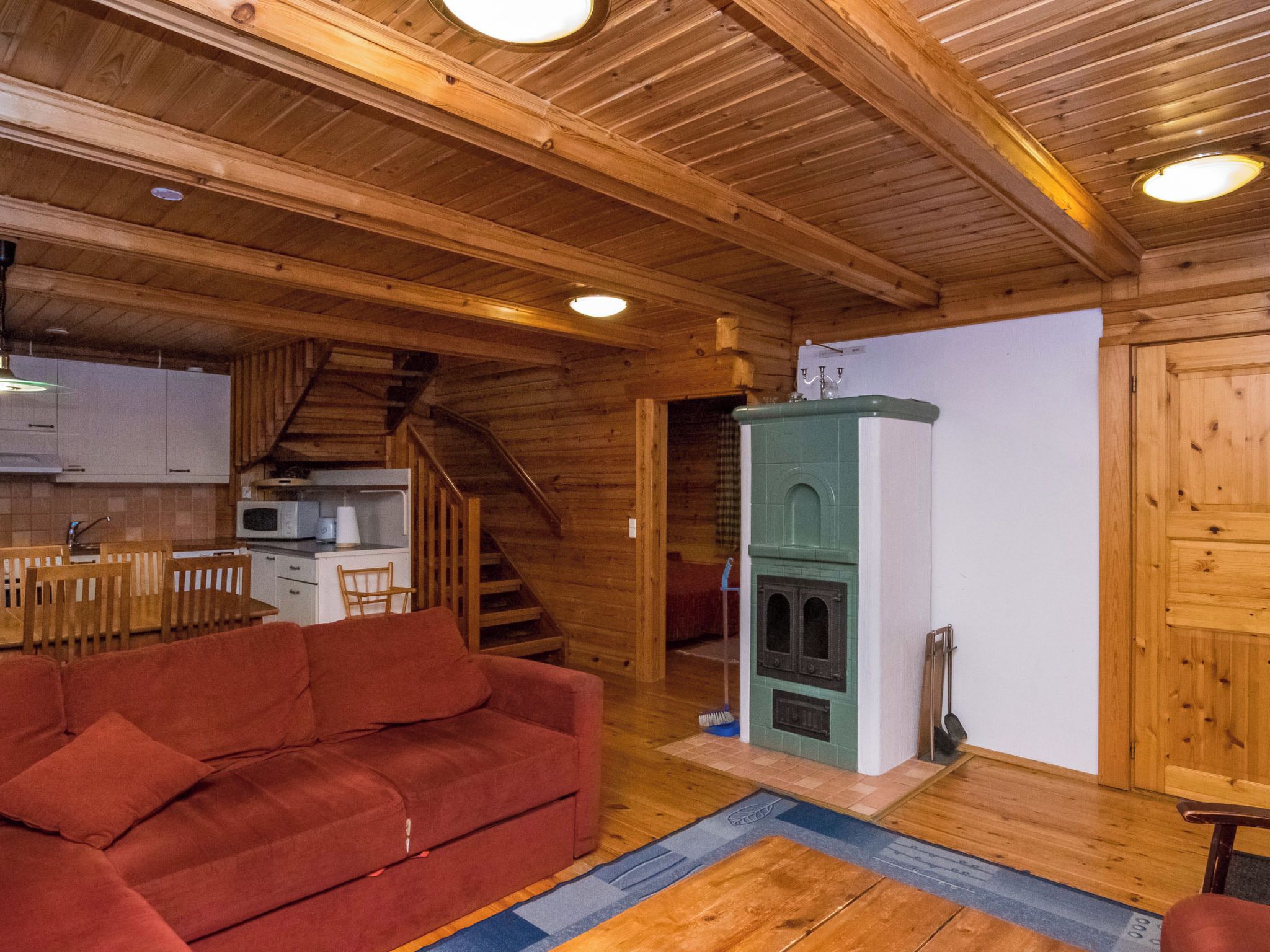 A wooden interior with a sofa, kitchen, and staircase.