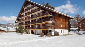 A multi-story hotel with balconies, a ski slope in the background, and a snowy landscape. - Opale 4 by Interhome (Villars)