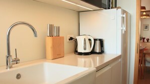 Een moderne keuken met een witte spoelbak, een roestvrijstalen kraan en een houten messenblok.