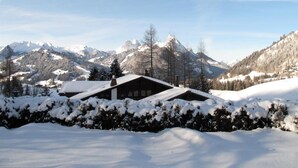 Eine verschneite Berglandschaft mit einer Hütte im Vordergrund.