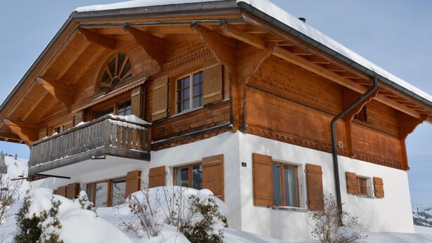 Eine große Holzhütte mit Balkon, umgeben von Schnee.