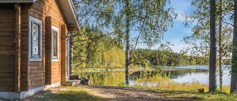 Eine Holzhütte mit Blick auf einen See und Bäume.