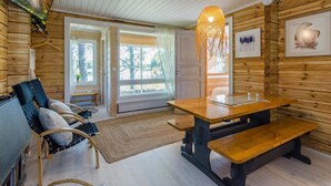 Interior acogedor de una cabaña con detalles de madera, un ventanal grande, una mesa de comedor y un banco.