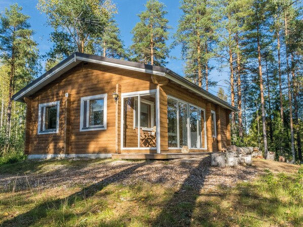 A wooden cabin with a large glass door, surrounded by a forest. - Sakarinniemi, vaikon loma 5 by Interhome (Kaavi)