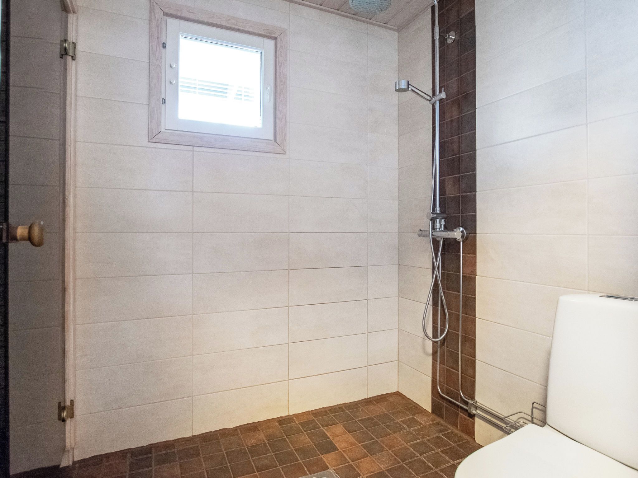 Ein Badezimmer mit Dusche, Toilette und einem Fenster.