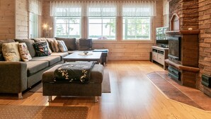 A cozy living room with a sofa, ottoman, and a fireplace. - Katajakallio by Interhome (Konnevesi)