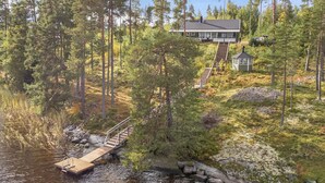 A lakeside cabin with a wooden dock and stairs leading to a house surrounded by dense forest. - Katajakallio by Interhome (Konnevesi)